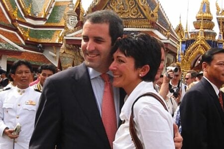 Ghislaine Maxwell smiles with Anthony Hilder at Bangkok's Grand Palace, with crowds and ornate temples in the background.