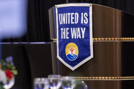 A United Way banner reading "UNITED IS THE WAY" hangs on a modern podium at an event.