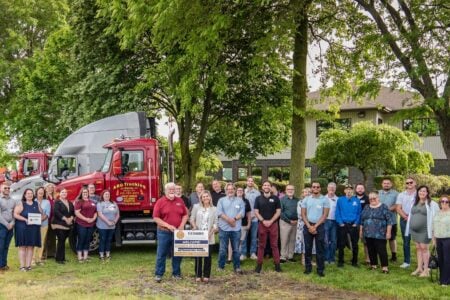 FLX Chamber and ARG Trucking staff pose outdoors with semi-trucks at a networking mixer.