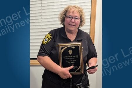 Correction Officer Judy Hoover of the Yates County Sheriff's Office smiles holding her 32-year retirement award.