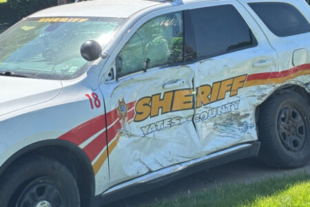Heavily damaged Yates County Sheriff's patrol vehicle with a shattered window and crumpled side.