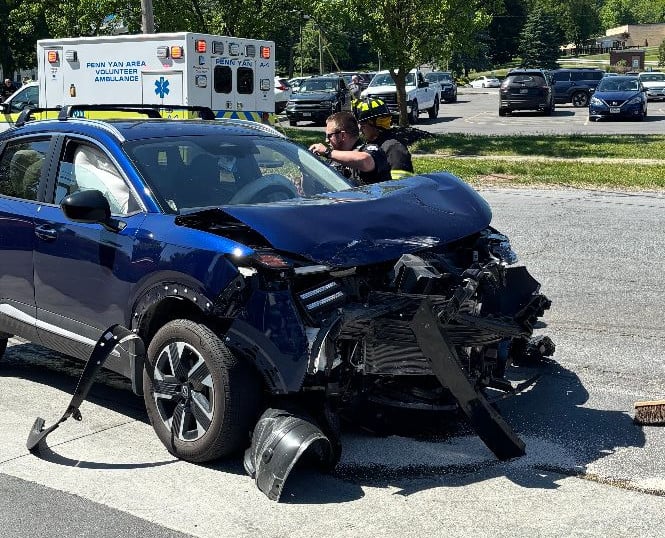 Emergency responders assess a heavily damaged blue SUV on a Penn Yan street after an accident.