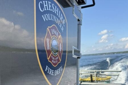 Cheshire Volunteer Fire Dept. boat displays its emblem while moving on a Finger Lake, creating a clear wake.