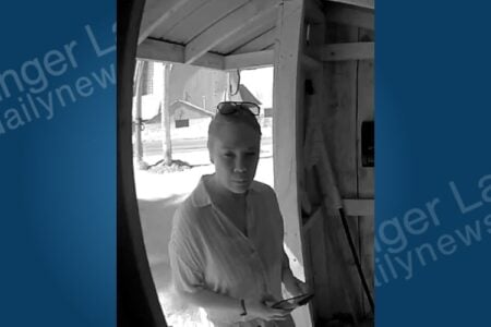 Grayscale footage shows a woman with sunglasses on her head, looking down at a phone under a porch.