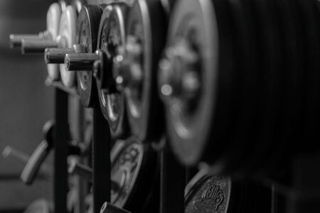 Black and white barbell weight plates line a rack at a gym.
