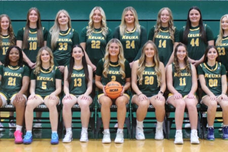 Fifteen Keuka women's basketball players pose for a team photo on the court, one holding a basketball.