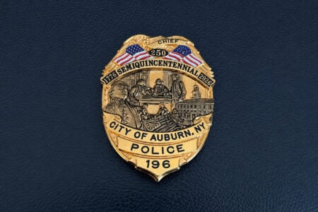 Gold City of Auburn, NY Police Chief badge for 1776-2026 Semiquincentennial on a dark blue background.