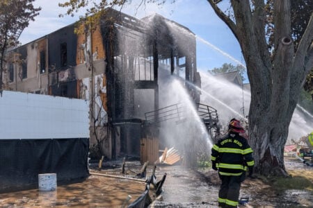 Crystal Beach firefighters douse a heavily charred two-story building with water.