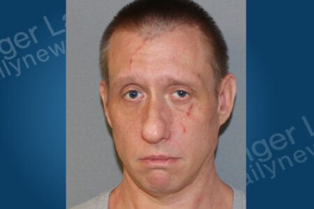 Mugshot of a man with short hair, multiple facial scratches, and a neutral expression, looking directly forward.