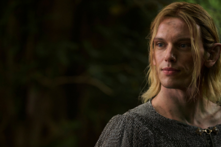 Blonde-haired man with pointed ears and a chainmail tunic looks right in a dark forest setting.