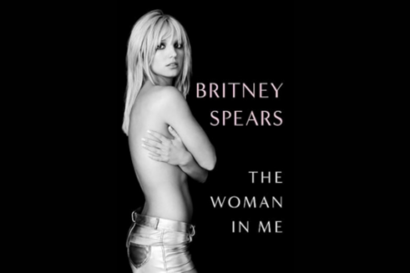 Britney Spears in black & white, bare-chested, arms crossed, wearing silver shorts. Title: 'BRITNEY SPEARS THE WOMAN IN ME'.