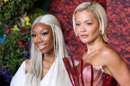 Brandy smiles next to Rita Ora at an event; Brandy has long blonde hair, Rita has short blonde hair.