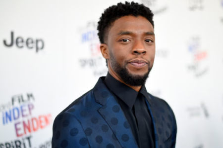 Chadwick Boseman in a blue polka-dot suit poses on a red carpet with "Jeep" and "Film Independent Spirit Awards" logos.