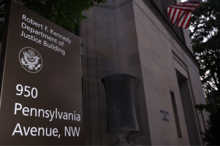 Sign for the Robert F. Kennedy Department of Justice Building, 950 Pennsylvania Avenue, NW, with the building and US flag.