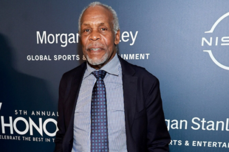 Danny Glover smiles in a suit against a blue backdrop with "Morgan Stanley" and "Nissan" logos visible.