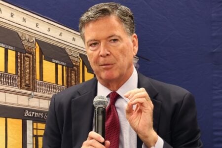 Former FBI Director James Comey speaks at a Barnes & Noble event, holding a microphone.