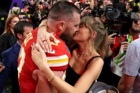 Travis Kelce in Chiefs jersey kisses Taylor Swift during a Super Bowl post-game celebration.