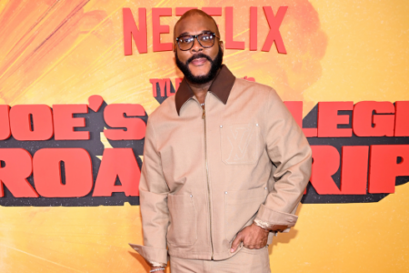 Tyler Perry, in glasses and a beige jacket, poses at a Netflix "Joe's Road Trip" event.