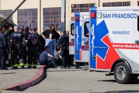 San Francisco emergency personnel and civilians gather near multiple AMR ambulances at an outdoor scene.