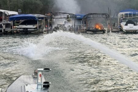 Firefighters battle a multi-boat blaze at a Finger Lakes marina, spraying water from a fireboat.