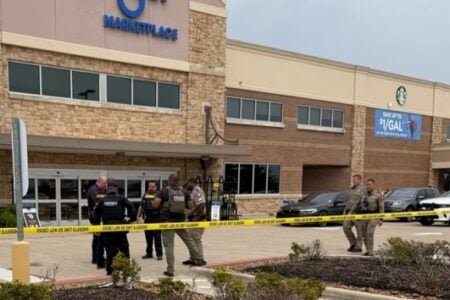 Sheriff's deputies and police officers secure an area with yellow "Do Not Cross" tape outside a Marketplace store.