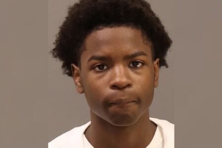 Young Black male with short curly hair looks directly at the camera in a mugshot.