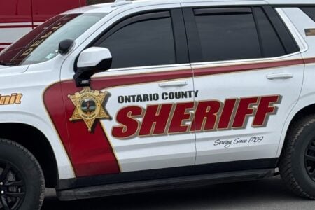 White Ontario County Sheriff vehicle with red and gold "SHERIFF" text and badge on the side.