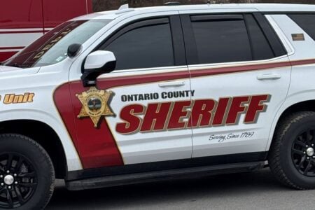 Side of a white Ontario County Sheriff's SUV, with red and gold lettering and a star emblem.