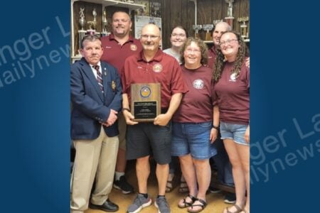 Cody Fuller accepts the Big Flats Fire Service Community Achievement Award alongside fire department members at an indoor ceremony.