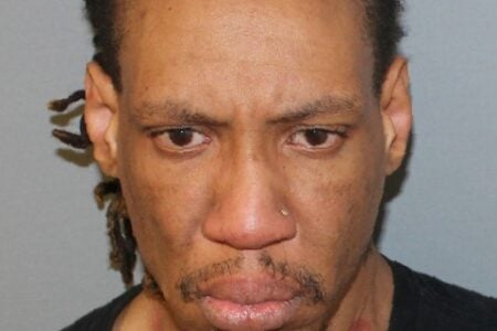Mugshot of a dark-skinned man with dark hair, a nose ring, mustache, goatee, and a reddish mark on his neck.