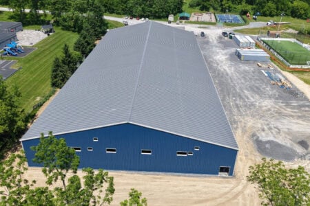 Aerial view of a newly constructed blue metal building with a gray roof at a Finger Lakes recreational facility.