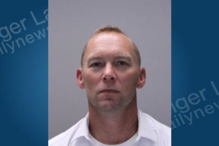 Man with short blonde hair, wearing a white collared shirt, looks directly at the camera for a mugshot.