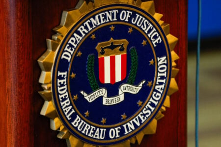 FBI seal for the Department of Justice and Federal Bureau of Investigation, displayed on a brown wooden podium.